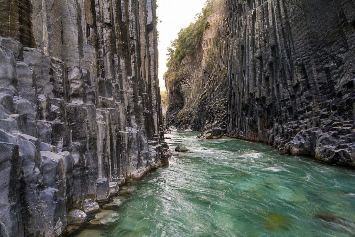 Dark basalt columns rising above the Alcantara river in the Alcantara Gorges